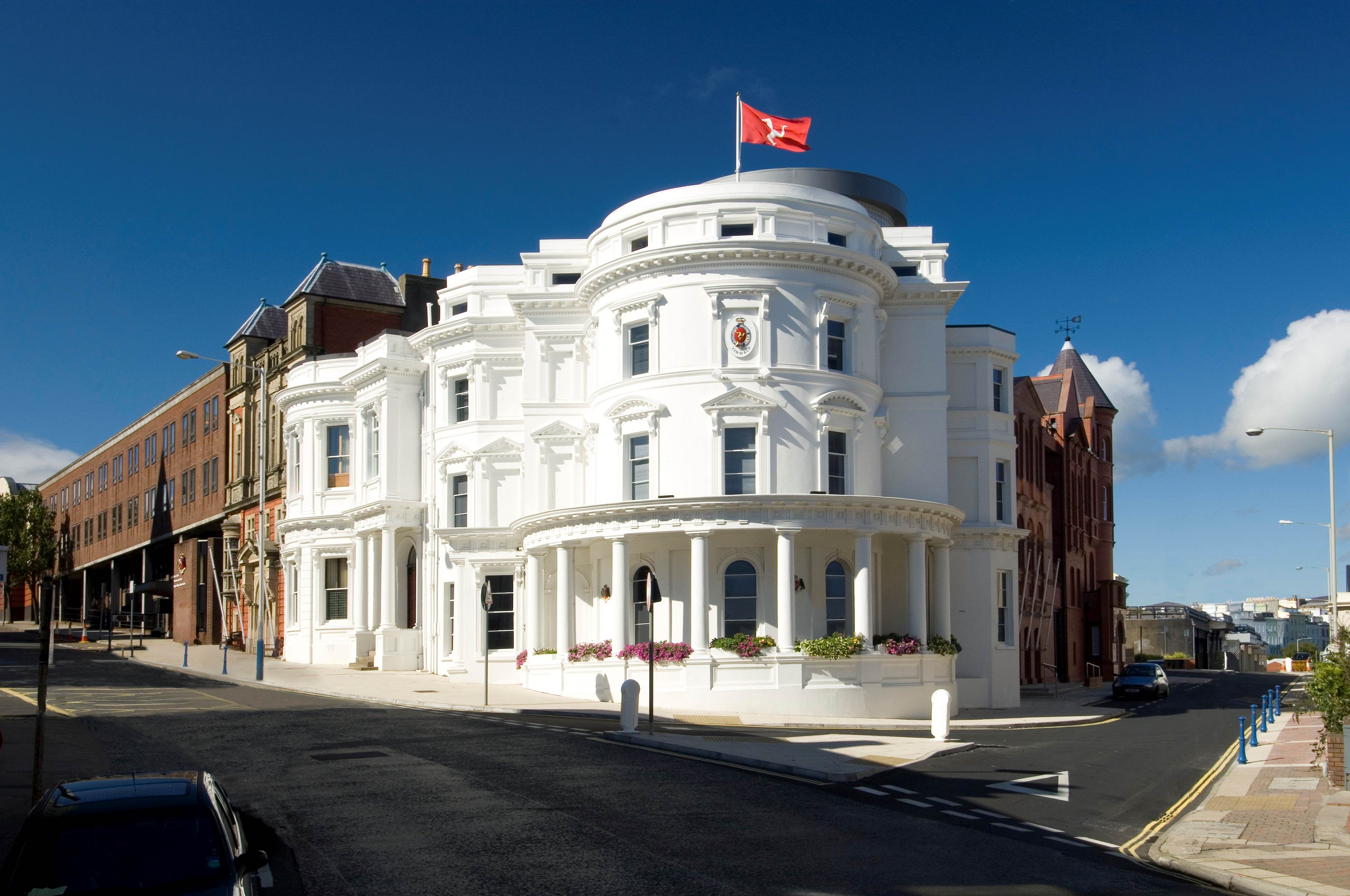 A photo of the Legislative Buildings of the Isle of Man, a large white rounded building on a street corner